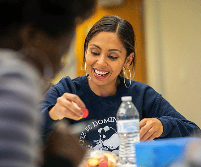 Teacher smiling with a math game piece in hand